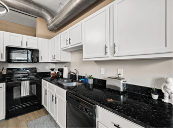 a kitchen with black counter tops and white cabinets